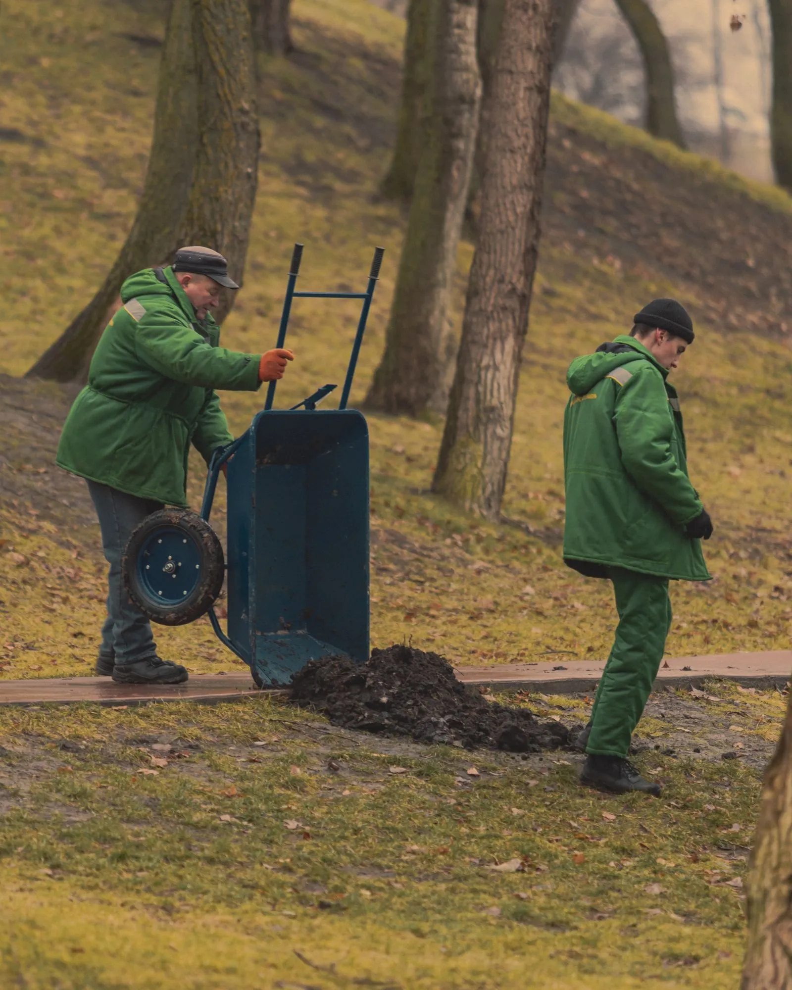 Twee hoveniers aan het werk met een kruiwagen